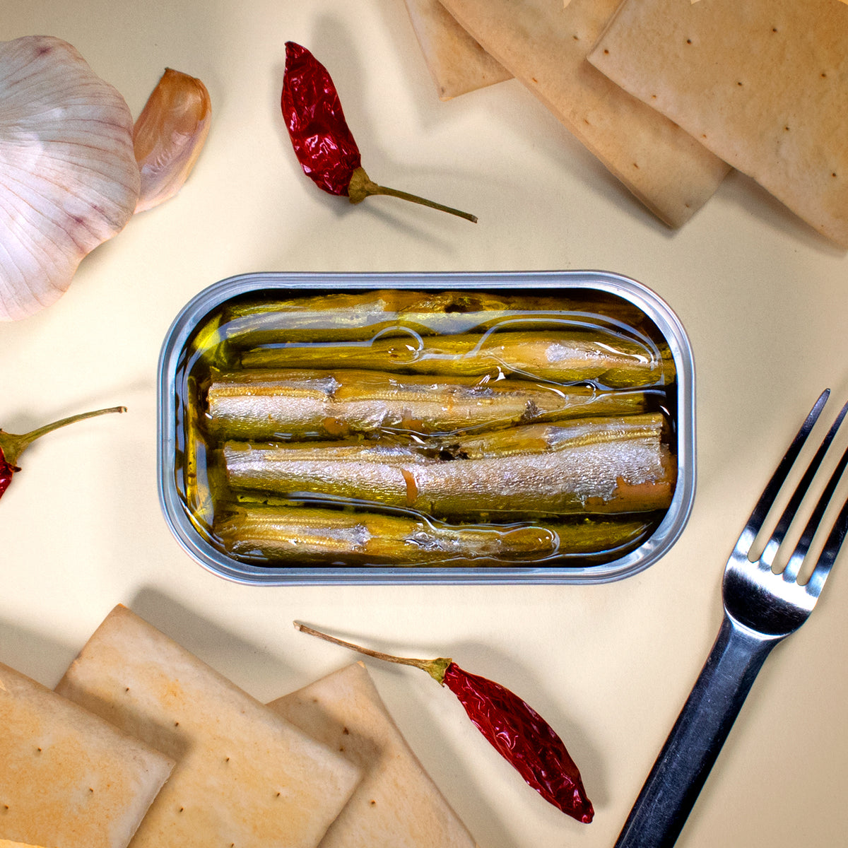 Öffnen Sie eine Dose HORNHECHT IN OLIVENÖL von José Gourmet mit Crackern, Knoblauch, roten Chilischoten und einer Gabel auf hellem Hintergrund für ein exquisites Meeresfrüchte-Geschmackserlebnis.