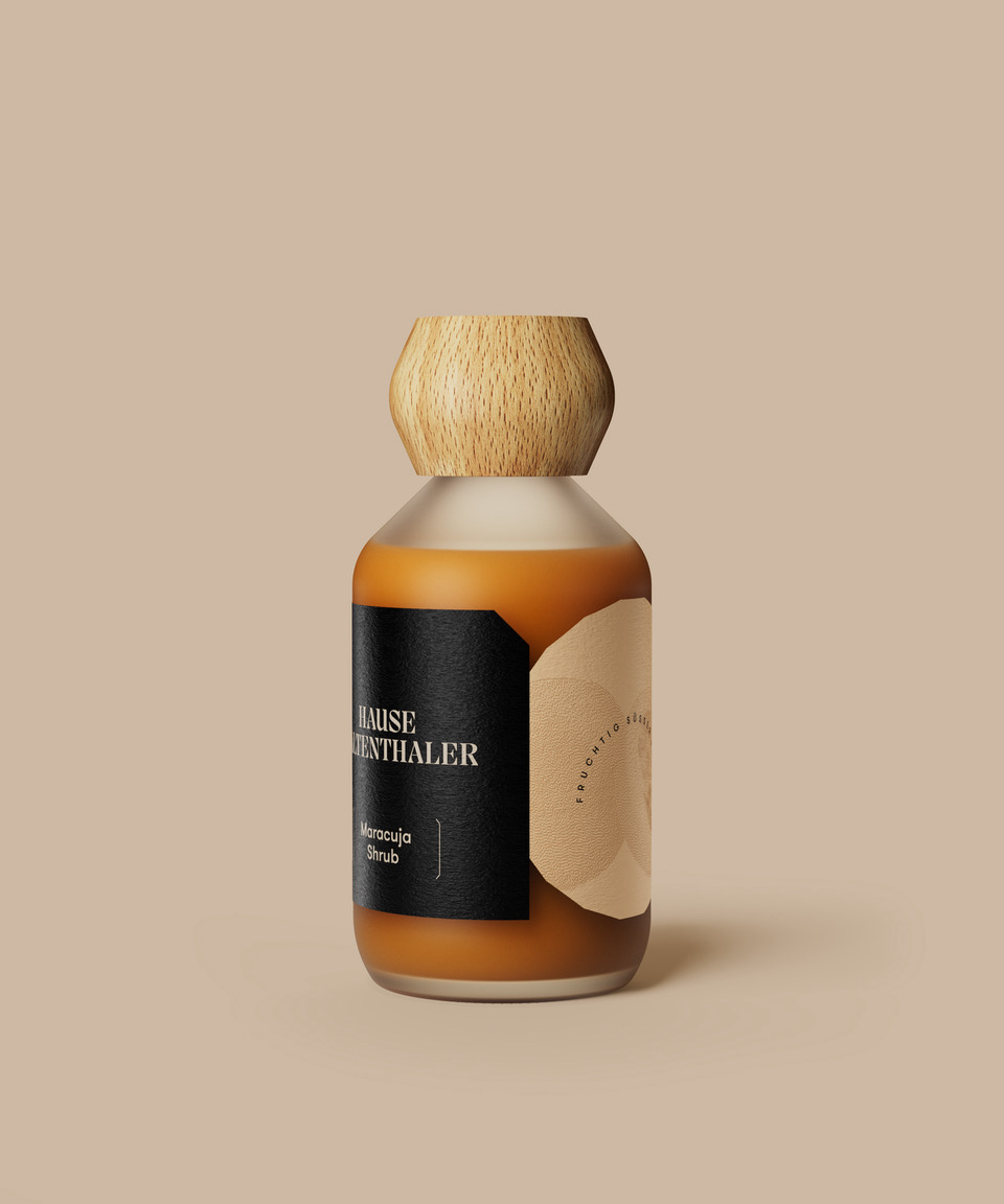 Eine Braunglasflasche mit Holzkappe und minimalistischem Etikett auf beigem Hintergrund, perfekt für die Präsentation des MARACUJA SHRUB von Haus Kaltenthaler oder anderer raffinierter Passionsfrucht-Spezialitäten.