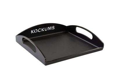 Die GRIDDLEPLATTE KOCKUMS 35 X 35 CM von Kockums Jernverk ist ein schwarzes Tablett aus schwedischem Kohlenstoffstahl mit ausgeschnittenen Griffen und dem „Kockums“-Logo auf der erhöhten hinteren Kante.
