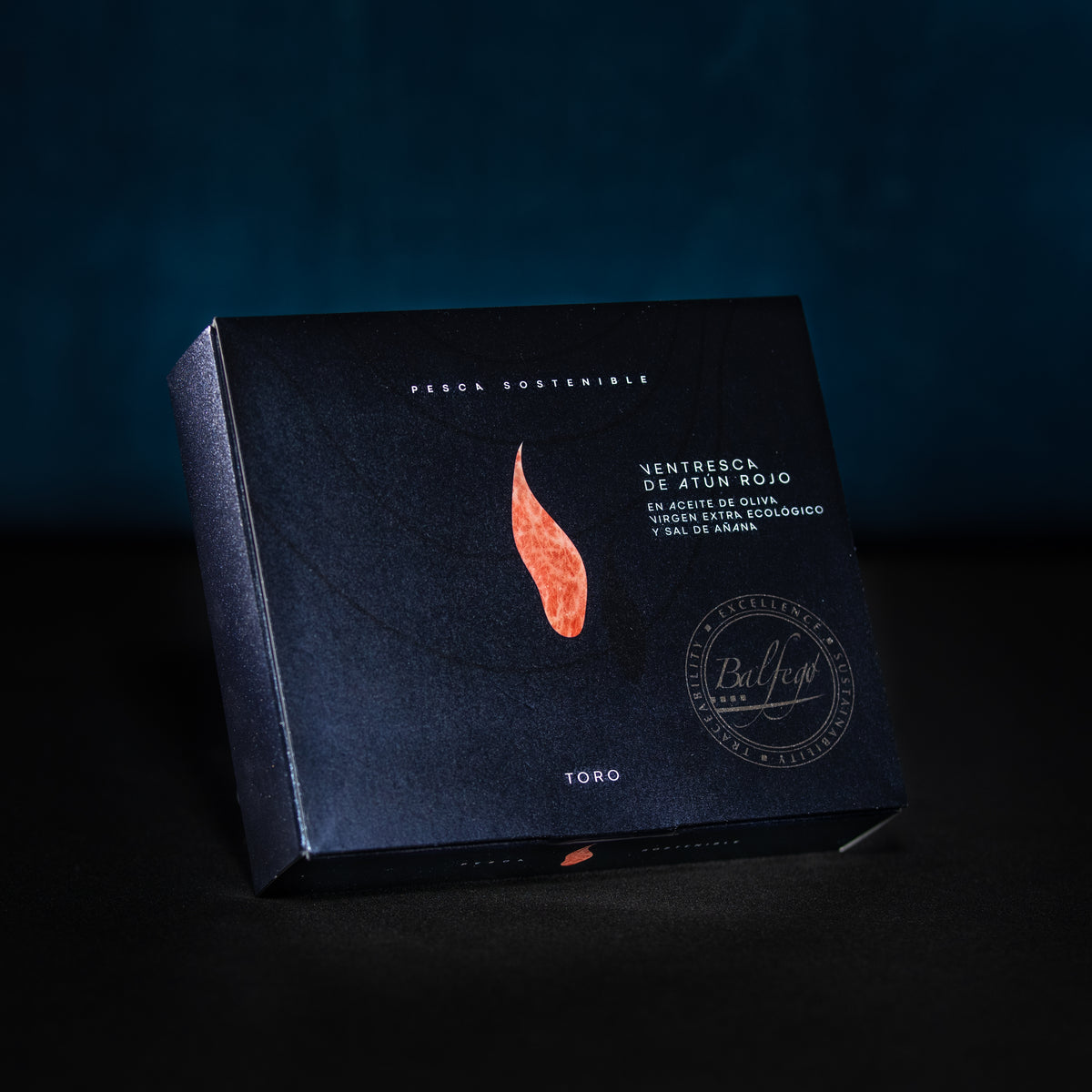 Der BALFEGO-THUNFISCHBAUCH IN OLIVENÖL von Balfego verfügt über eine dunkle Verpackung mit elegantem Design, einschließlich einer roten Fischgrafik und einem spanischen Text, der Balfegos Engagement für nachhaltigen Thunfisch (nachhaltiger Fang) betont.