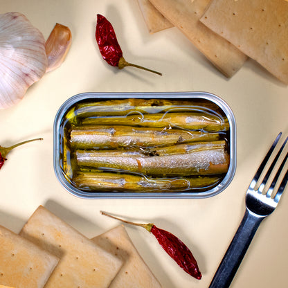 Öffnen Sie eine Dose HORNHECHT IN OLIVENÖL von José Gourmet mit Crackern, Knoblauch, roten Chilischoten und einer Gabel auf hellem Hintergrund für ein exquisites Meeresfrüchte-Geschmackserlebnis.