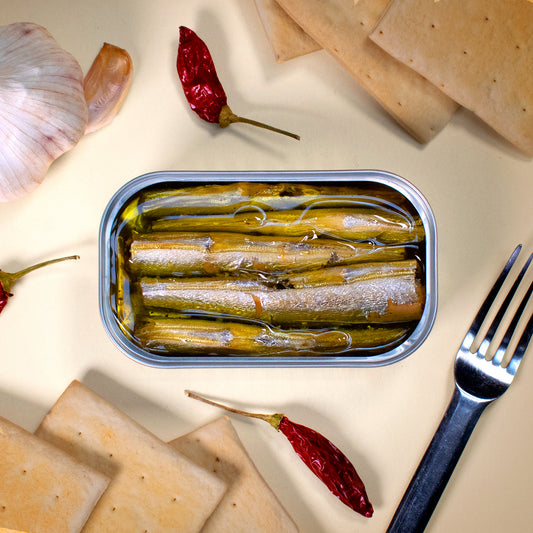 Öffnen Sie eine Dose HORNHECHT IN OLIVENÖL von José Gourmet mit Crackern, Knoblauch, roten Chilischoten und einer Gabel auf hellem Hintergrund für ein exquisites Meeresfrüchte-Geschmackserlebnis.